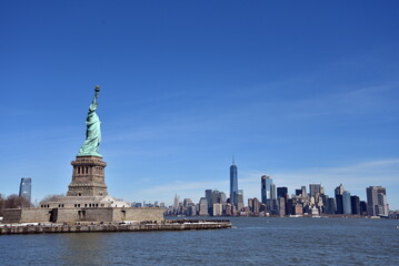 Statue of Liberty on Liberty Island with Lower Manhattan skyline under a clear blue sky in New York City, USA © rbkgm146