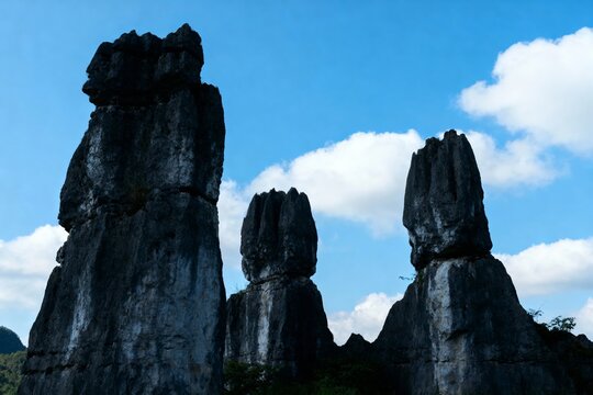 Tall limestone rock formations rising against a blue sky with scattered clouds