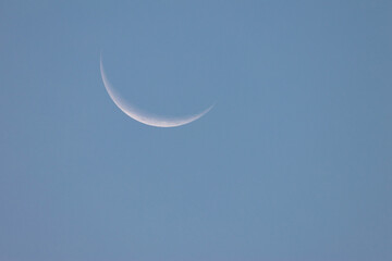 Minimalist shot of a delicate crescent moon glowing in the expansive sky © CesareFerrari