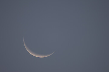 Minimalist shot of a delicate crescent moon glowing in the expansive sky © CesareFerrari