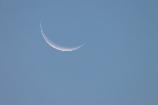 Minimalist shot of a delicate crescent moon glowing in the expansive sky