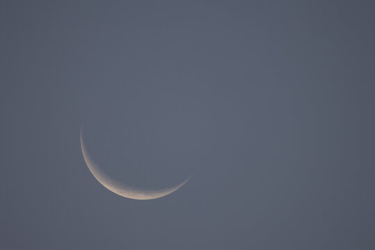 Minimalist shot of a delicate crescent moon glowing in the expansive sky