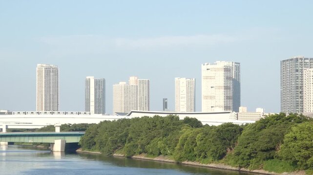 A panning shot capturing a long-distance view of a new transit system and buildings in Koto Ward, Tokyo, moving from right to left.