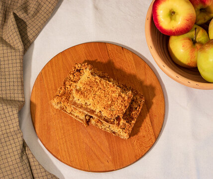 An apple grated pie with cinnamon. Flat lay of ann apple pie on a wooden board, green tea towel and a basket with apples.