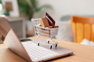 Online shopping ecommerce delivery and digital internet payment concept. Miniature cart with boxes and credit card on laptop computer keyboard. © Kiattisak