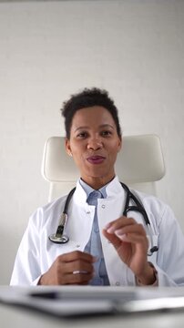 Friendly female physician speaking and listening to patient during virtual medical appointment. Warm professional communication in remote healthcare consultation