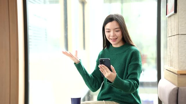 Young Asian woman working on a laptop in a bright modern cafe, representing remote work, digital business, productivity, technology, and contemporary lifestyle.