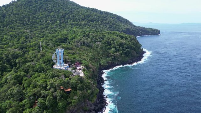 Weh Island, Indonesia : Aerial drone footage of 0 kilometer monument in Weh island of Aceh, Indonesia surrounded by rain forest. Taken with forward motion showing wave from Andaman sea breaks into roc