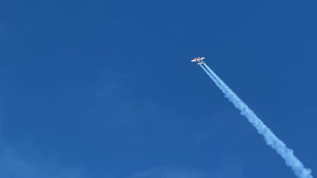 Stunt Plane Performing Aerobatics with Smoke Trail in Blue Sky