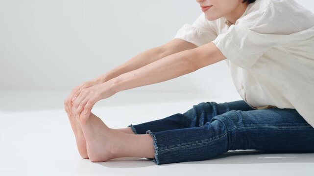 A middle-aged woman bending forward. Stretching, flexibility, gymnastics, softness, exercise, fitness, training, foot care