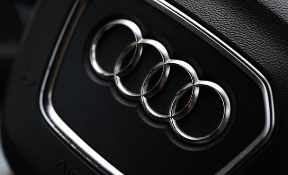 Belarus, Bobruisk 15.07.2026: A close-up of the four interlocking metal rings of the Audi brand on a textured black surface, forming the emblem of the luxury car manufacturer