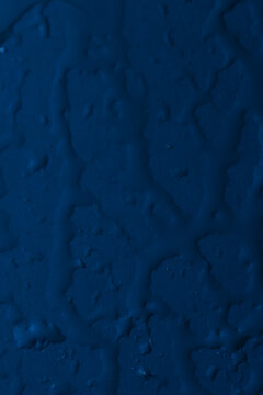 Broad winding water streaks on a dark blue surface with scattered droplets.
