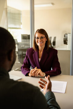Vertical photo of business woman meeting man at job interview in office, hr manager talking with candidate. Diverse multiracial recruitment conversation with resume document, copy space, specialists.