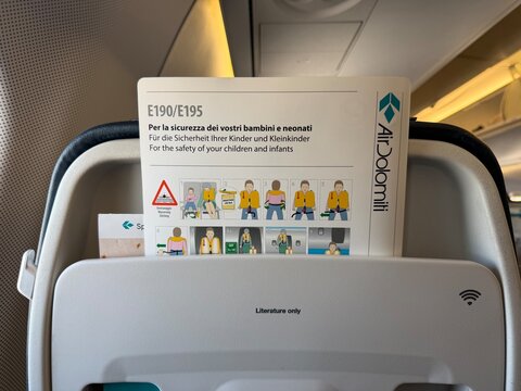 24 April 2026, Germany, Bavaria, Munich MUC - Air Dolomiti safety card for Embraer E190 E195 airplane inside front seat with informations in an emergency
