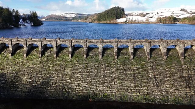 Scenic winter footage of Lake Vyrnwy reservoir in Wales, featuring snow-covered landscape, water, woodland and the historic dam and surrounding streams.
