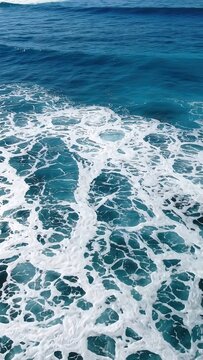 Ocean waves crashing against the shore create a dynamic flow of foam and water, showcasing the vibrant blue hues of the sea in a coastal environment