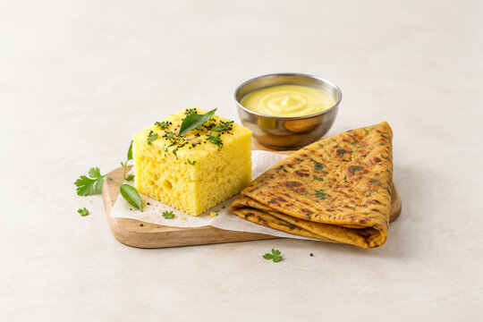 Steamed dhokla square with thepla flatbread and chickpea batter bowl, retail food display