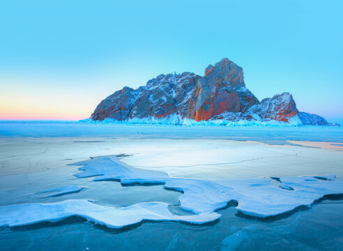 Beautiful winter landscape of frozen Lake Baikal at sunrise - A granite rock with steep slopes rises above a frozen lake - Baikal lake, Siberia