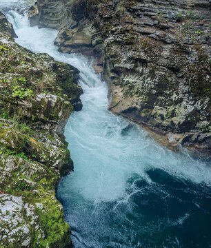 clear blue river water rushing through moss covered rocky canyon gorge in natural forest setting