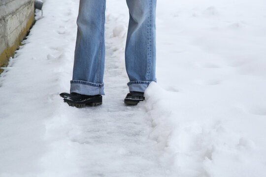 Danger of slipping. Person in chunky platform leather boots walking on snowy icey road