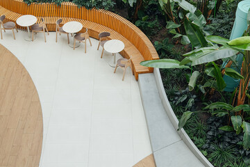 Outdoor seating area with tables and chairs next to a lush green plant display