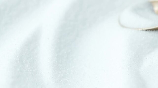 White salt crystals pouring out of a spoon in slow motion