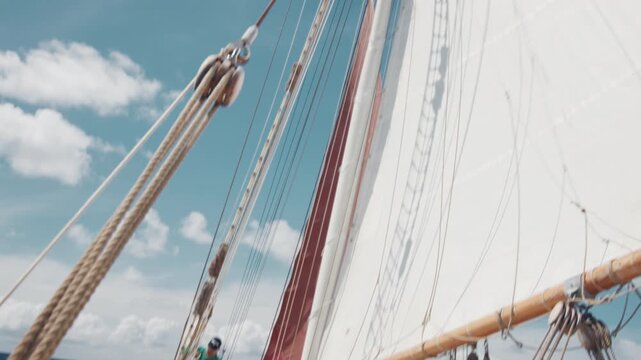 Crew work with the sails on the big expeditional sailing vessel moving in the Atlantic Ocean