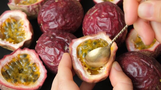 Close up of spoon scooping juicy pulp out of passion fruit shell