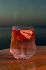 Obraz premium Strawberry lemonade with lime and fresh mint overlooking the sea at sunset 