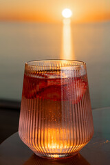 Obraz premium Strawberry lemonade with lime and fresh mint overlooking the sea at sunset 