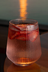 Obraz premium Strawberry lemonade with lime and fresh mint overlooking the sea at sunset 