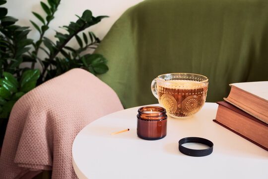 Living room setting with lit candle, tea and books on white table