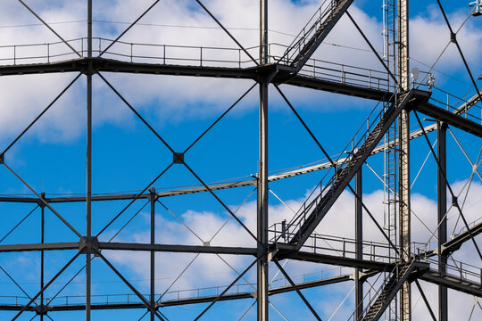 Industrial steel framework and circular structural geometry rise against a vivid blue sky with intersecting lines and open mechanical architecture