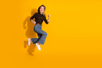Fototapeta premium Young woman jumping in casual fashion on a bright yellow background for lifestyle and advertising use