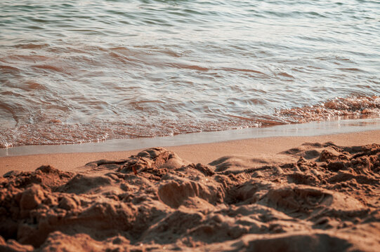Gentle waves reaching a sandy beach with textured wet sand