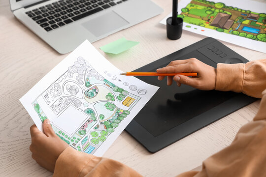 Landscape design and architecture planning, professional designer working on garden project with digital tablet and paper sketch at office desk