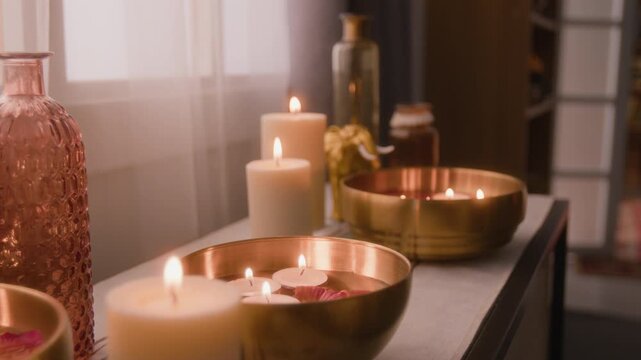 Burning candles and floating tealights flickering in brass water bowls during relaxation ritual. Footage suitable for spa advertising, meditation apps and wellness retreat marketing campaigns