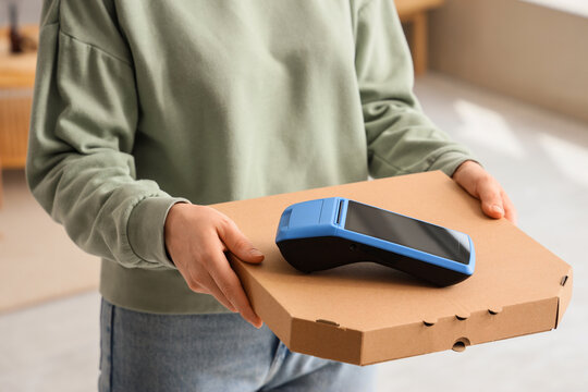 Contactless food delivery and payment, courier holding pizza box with mobile card terminal for secure transaction at home or office door