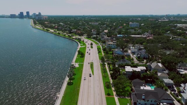 Drone shot of the sweeping curve of Bayshore Boulevard in Tampa, Florida, framed by luxury waterfront homes, palm-lined streets, and the calm waters of Hillsborough Bay.