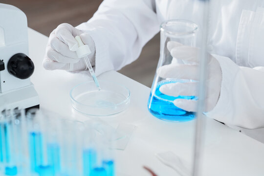 Medical research and pharmaceutical development, scientist using pipette and petri dish with blue liquid in laboratory for clinical testing and analysis