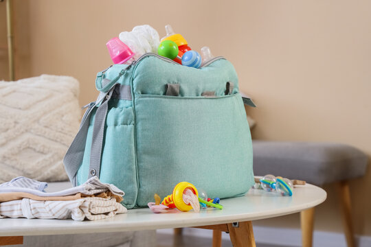Baby bag with accessories and rattles on table in living room
