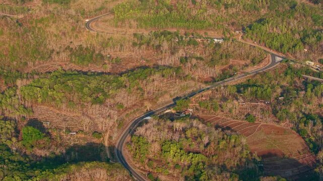 Aerial view of a winding road through the forested hills of Gunungkidul Regency, Special Region of Yogyakarta, Indonesia.