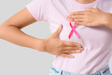 Young woman with pink ribbon on white background, closeup. Breast cancer awareness concept