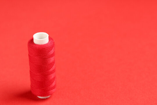 Spool of thread on red background