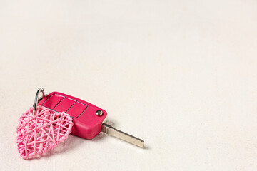Obraz premium Car key with pink heart on white background