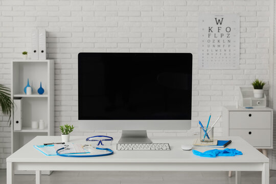 Blank computer monitor with doctors supplies on desk in medical office