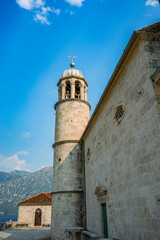 Obraz premium Historic stone bell tower against mountains and blue sky