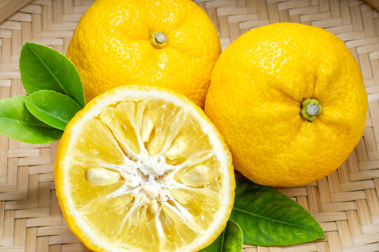 Fresh Sweet Yuzu Orange fruit in wooden basket over wooden background, Yuzu Orange fruit, Citron citrus on wooden background, gourmet food recipes, and product packaging design.