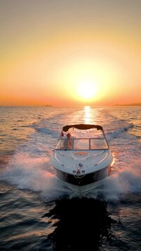 Front view tracking of a motor speedboat cruising over the calm ocean during golden sunset time
