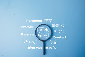 Magnifying glass with a translation icon and various language words on a blue background. Concept of multilingual communication, language learning, global localization, and translation service. © Pakorn